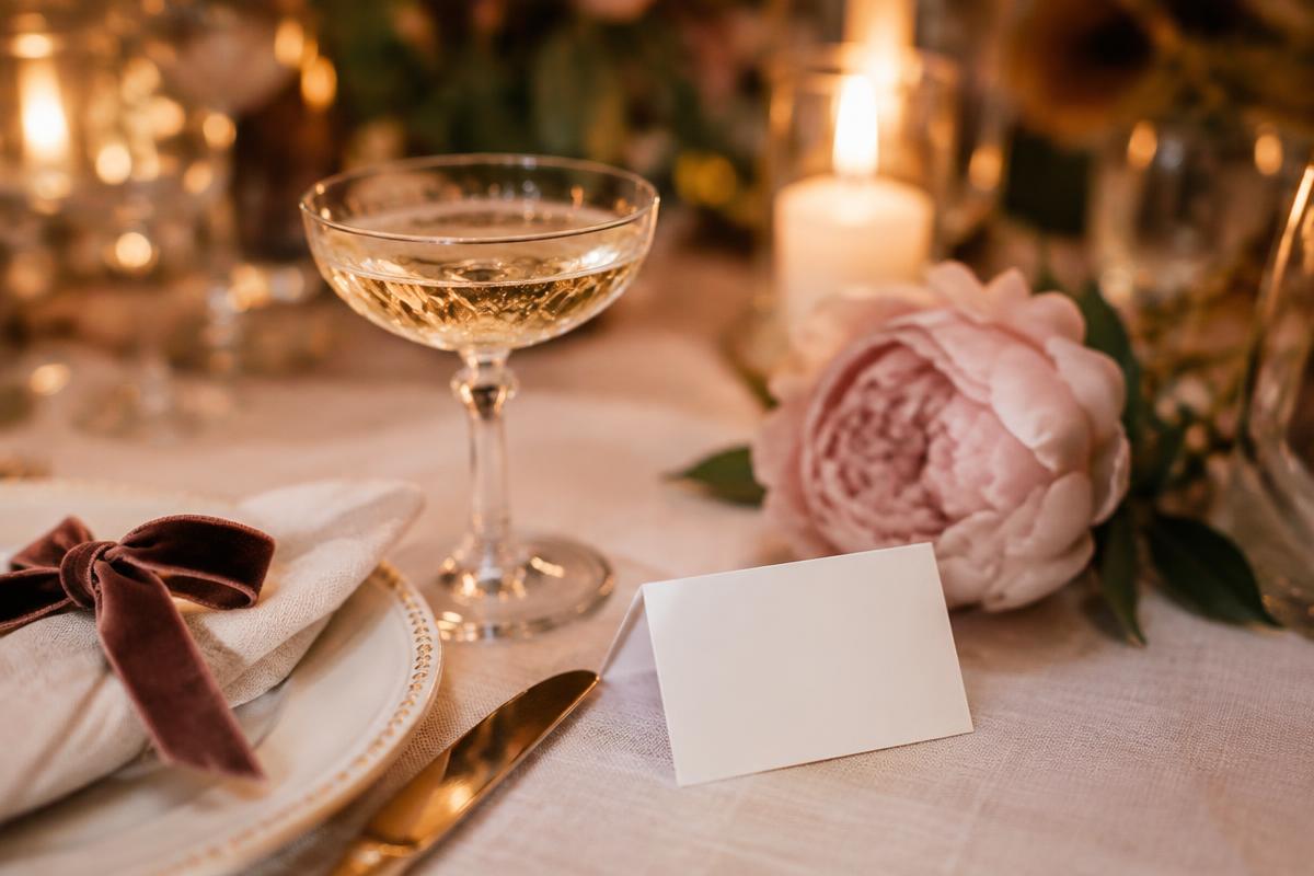 Celebration detail with champagne coupe, blush peony and velvet ribbon